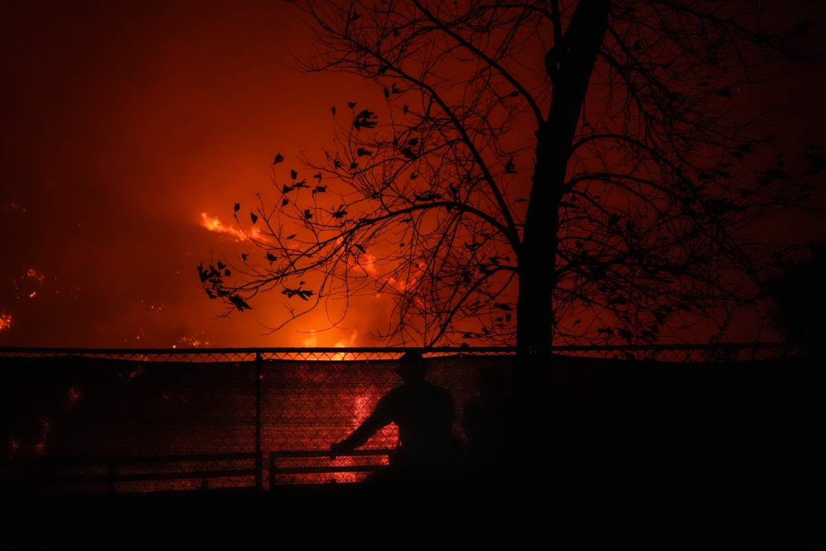 Two firefighters watch the Franklin Fire as it approaches a building in Malibu, Calif., Tuesday, Dec. 10, 2024.