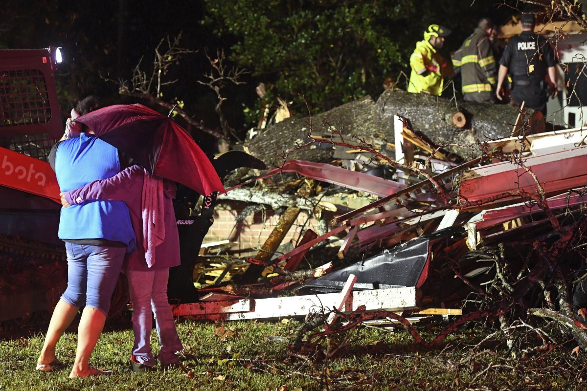 Bystanders hug as first responders work to free a victim after a tree fell on a house in Natchez, Miss., Saturday, Dec. 28, 2024.