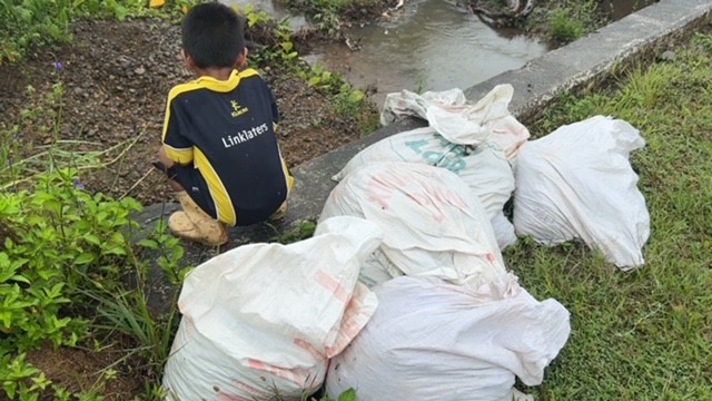 A young Vunaniu village resident watches on as climate preparedness efforts are taken to reduce flooding impacts to his home.