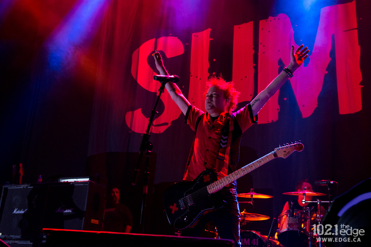 Deryck Whibley performs on stage with his hands in the air.