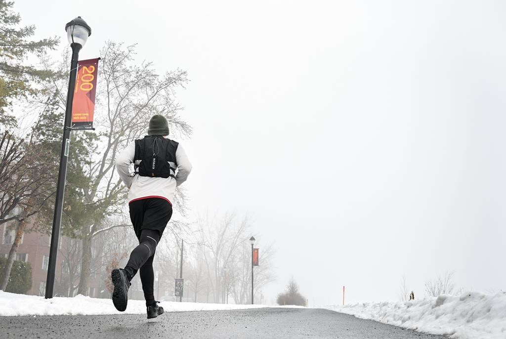 A person jogs by a sign celebrating the 200-year anniversary of the Lachine Canal in Montreal, Sunday, Dec. 29, 2024. Work on the canal began in 1821 and officially opened in 1825.