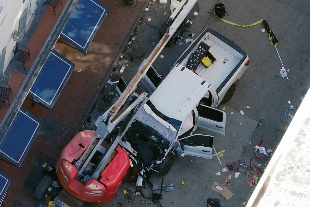 A black flag with white lettering lies on the ground rolled up behind a pickup truck that a man drove into a crowd on Bourbon Street in New Orleans. (AP Photo/Gerald Herbert)