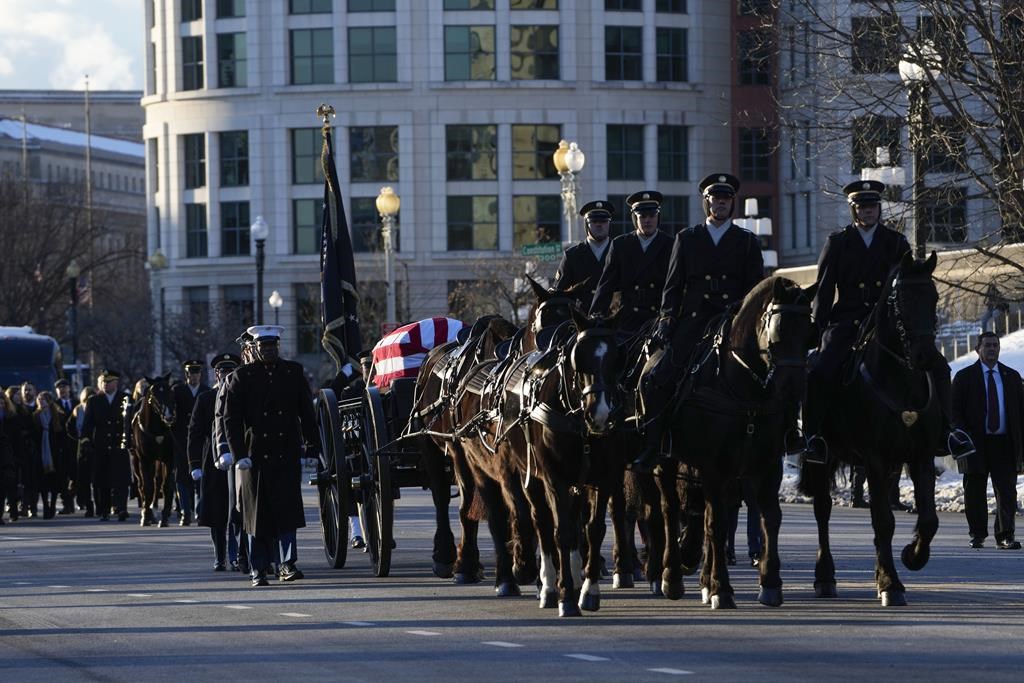 The casket containing the remains of former President Jimmy Carter moves on Constitution Avenue toward the U.S. Capitol on a horse-drawn caisson in Washington, Tuesday, Jan. 7, 2025. Carter died Dec. 29, 2024, at the age of 100. (AP Photo/Susan Walsh, Pool)