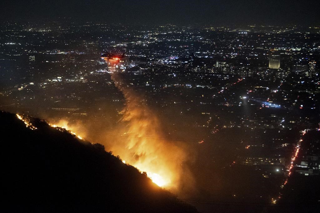 Water is dropped by helicopter on the burning Sunset Fire in the Hollywood Hills section of Los Angeles, Wednesday, Jan. 8, 2025.