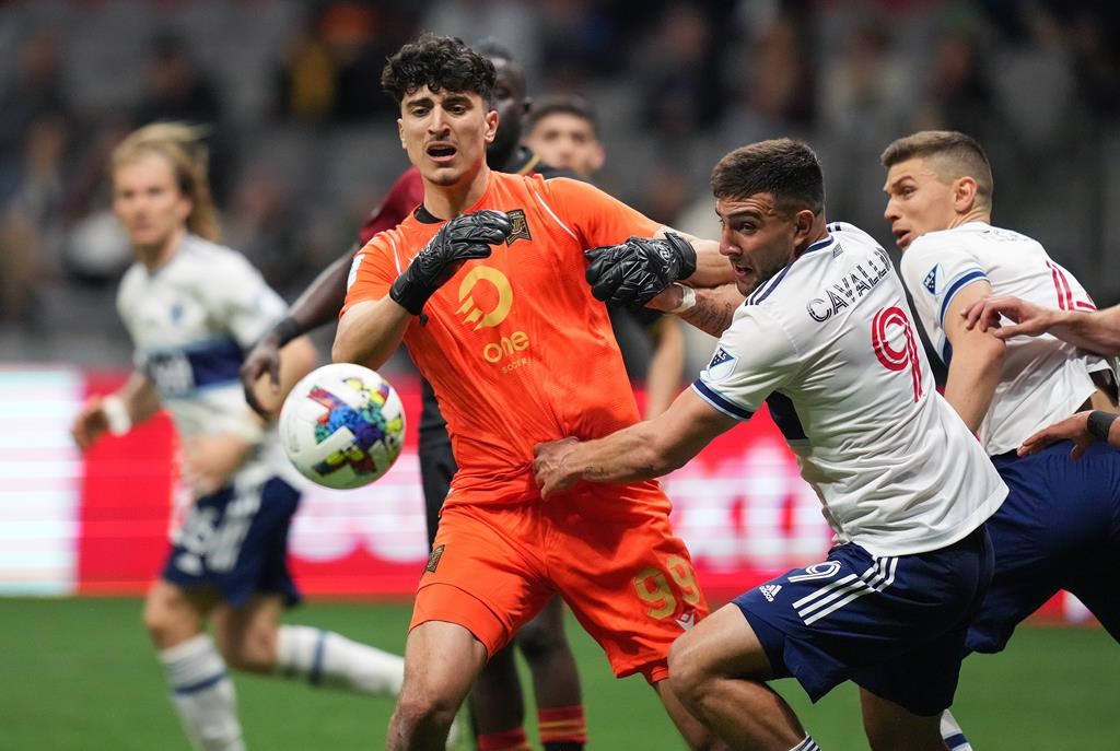 Valour FC goalkeeper Rayane Yesli, left, and Vancouver Whitecaps' Lucas Cavallini vie for the ball during the second half of a preliminary round Canadian Championship soccer match, in Vancouver, on Wednesday, May 11, 2022. THE CANADIAN PRESS/Darryl Dyck.