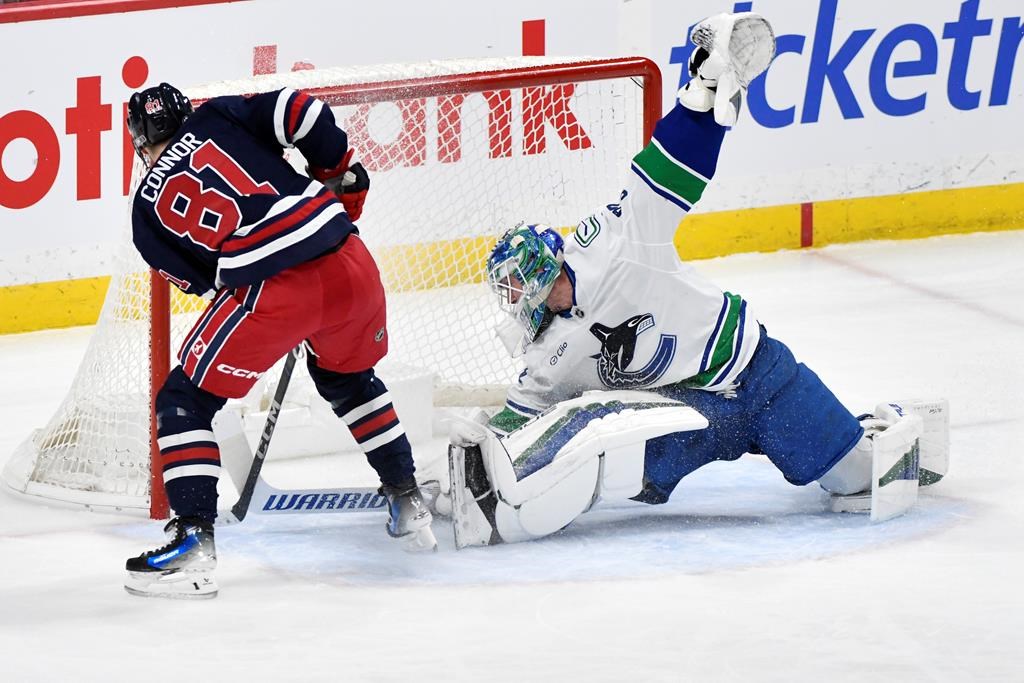 Winnipeg Jets’ Kyle Connor (81) scores his third goal of the period against Vancouver Canucks goaltender Kevin Lankinen (32) during the first period of their NHL hockey game in Winnipeg, Tuesday Jan. 14, 2025. THE CANADIAN PRESS/Fred Greenslade