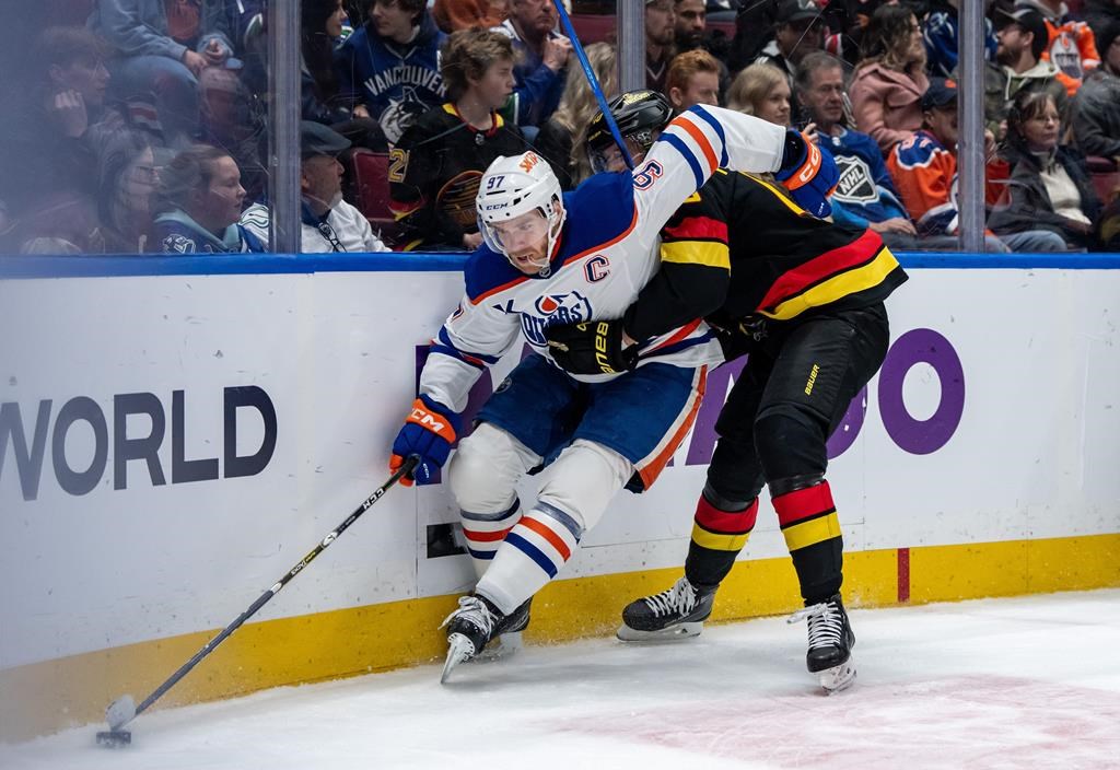 Edmonton Oilers' Connor McDavid (97) and Vancouver Canucks' Elias Pettersson (40) vie for the puck during third period NHL hockey action in Vancouver, B.C., Saturday, Jan. 18, 2025.