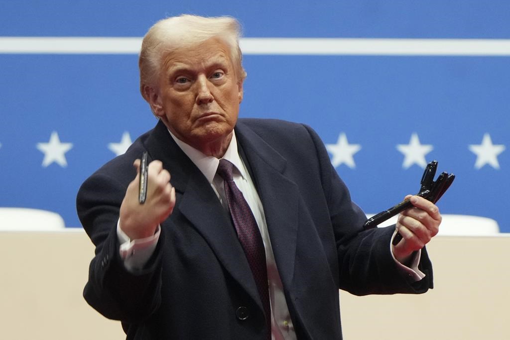 President Donald Trump throws pens used to sign executive orders to the crowd during an indoor Presidential Inauguration parade event in Washington, Monday, Jan. 20, 2025.