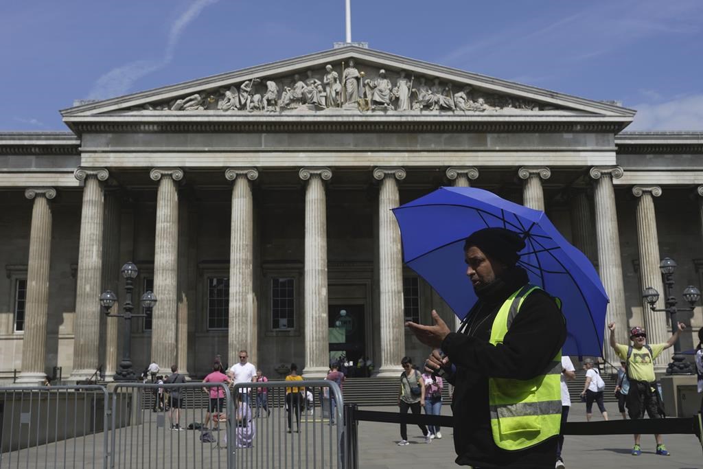 FILE - A worker holding an umbrella guides tourists at the British Museum, in Central London, Monday, June 12, 2023. (AP Photo/Kin Cheung, File).