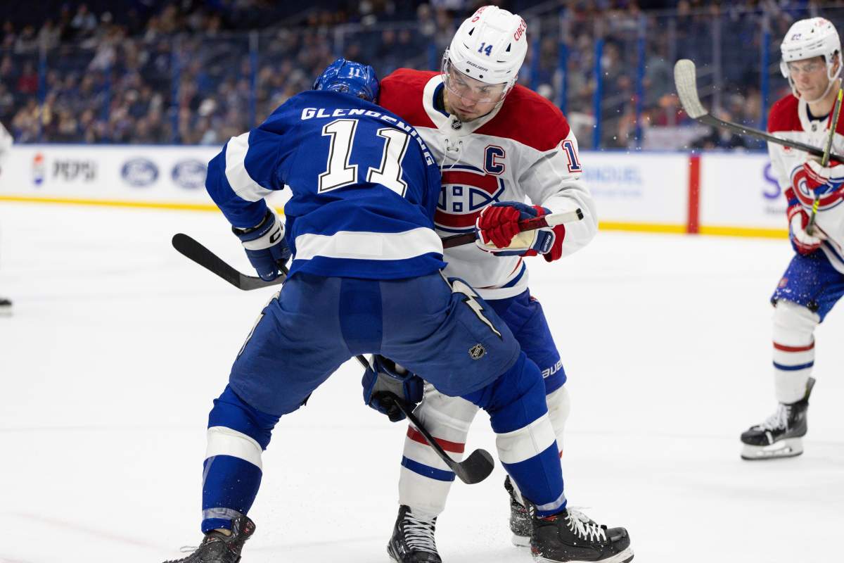 Montreal Canadiens center Nick Suzuki (14) checks Tampa Bay Lightning center Luke Glendening (11) during the third period of an NHL hockey game, Sunday, Dec. 29, 2024, in Tampa, Fla.