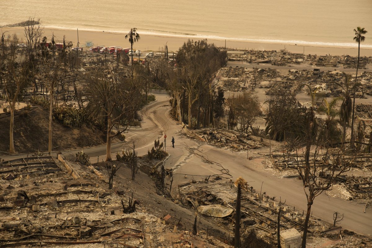 A person walks down a street in the aftermath of the Palisades Fire in the Pacific Palisades neighborhood of Los Angeles, on Saturday, Jan. 11, 2025.