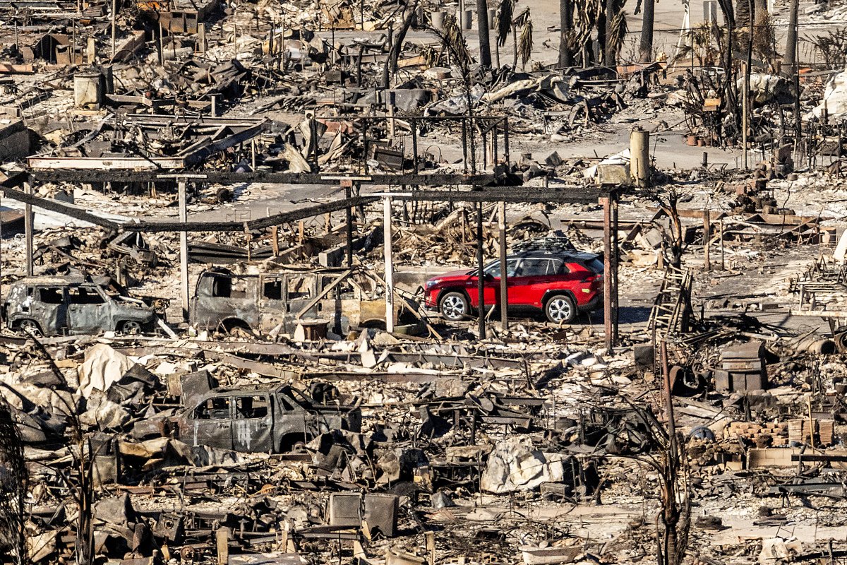 A car drives past homes and vehicles destroyed by the Palisades Fire at the Pacific Palisades Bowl Mobile Estates on Sunday, Jan. 12, 2025, in Los Angeles.