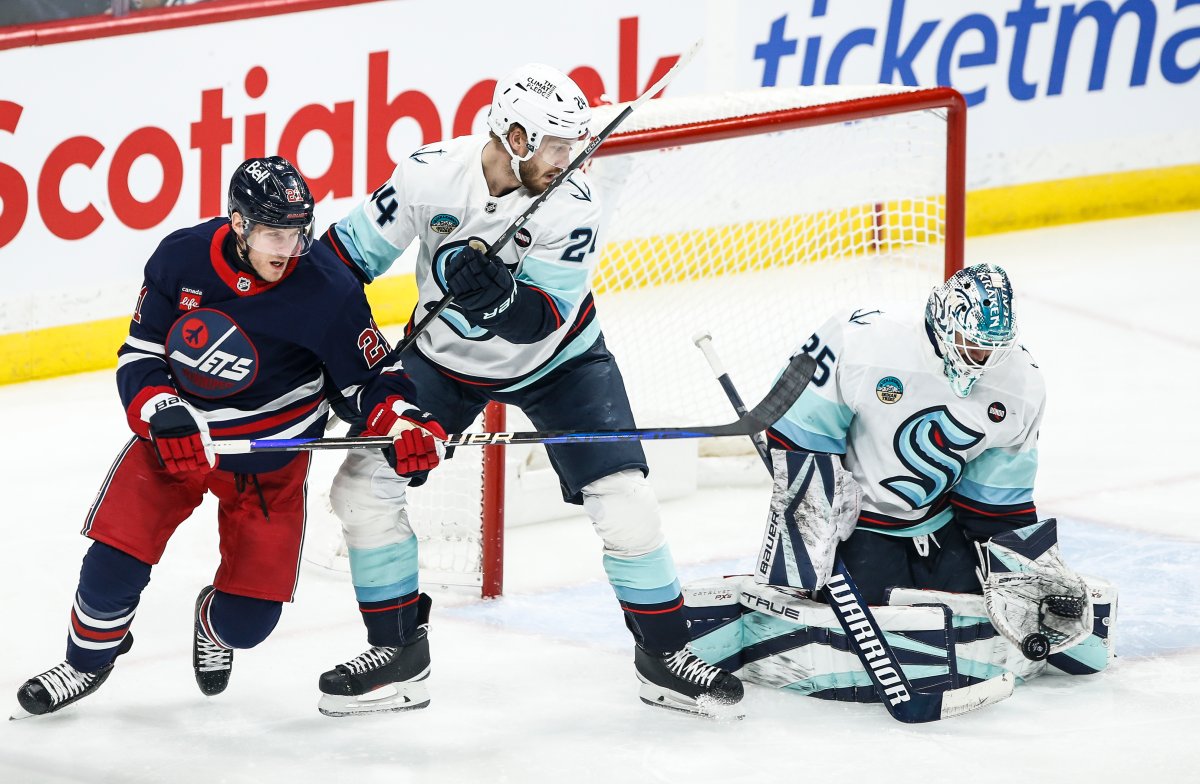 Seattle Kraken's Jamie Oleksiak (24) defends against Winnipeg Jets' Nikolaj Ehlers (27) as goaltender Joey Daccord (35) saves the shot during first period NHL action in Winnipeg on Thursday, January 16, 2025. THE CANADIAN PRESS/John Woods.