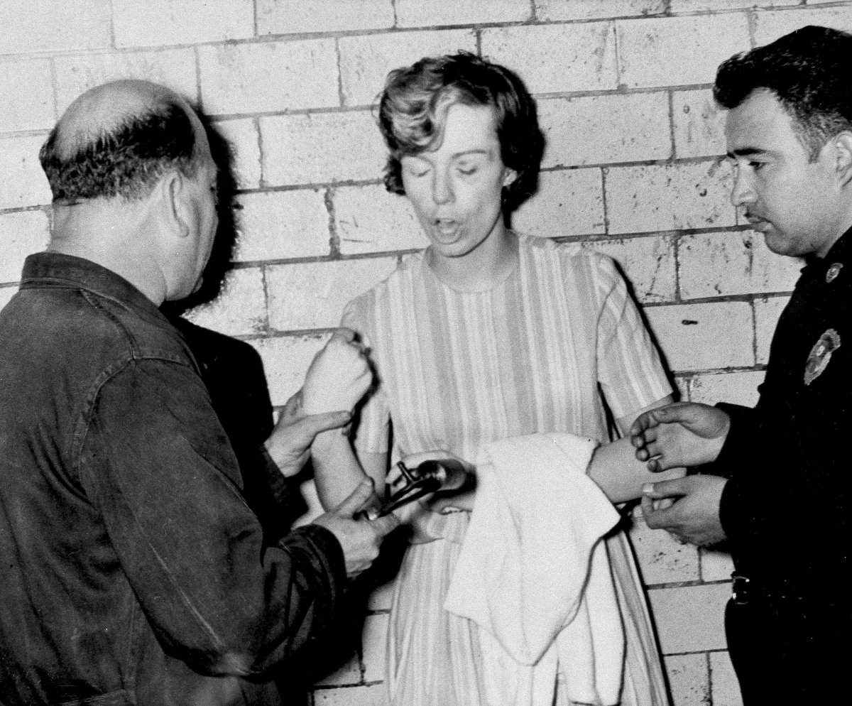 FILE – Sharon Elizabeth Kinne of Independence, Mo., refuses to have her fingerprints taken in Mexico City, Sept. 21, 1964. At left, trying to move her arm, fingerprint expert Guillermo Resendiz Ocampo, and at right is Lt. Angel Santamaria Lopez of the Federal Police.