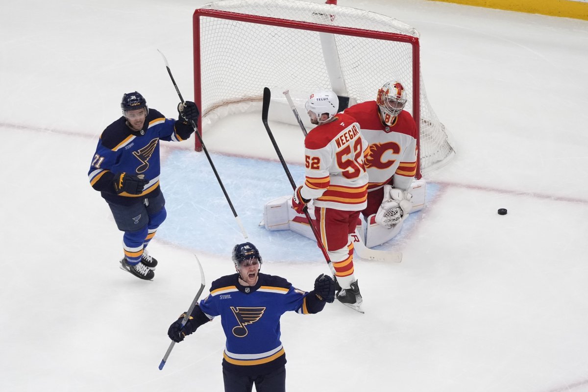 St. Louis Blues' Radek Faksa, bottom, celebrates after scoring past Calgary Flames' MacKenzie Weegar (52) and goaltender Dan Vladar (80) as teammate Mathieu Joseph (71) looks on during the third period of an NHL hockey game Tuesday, Jan. 14, 2025, in St. Louis.