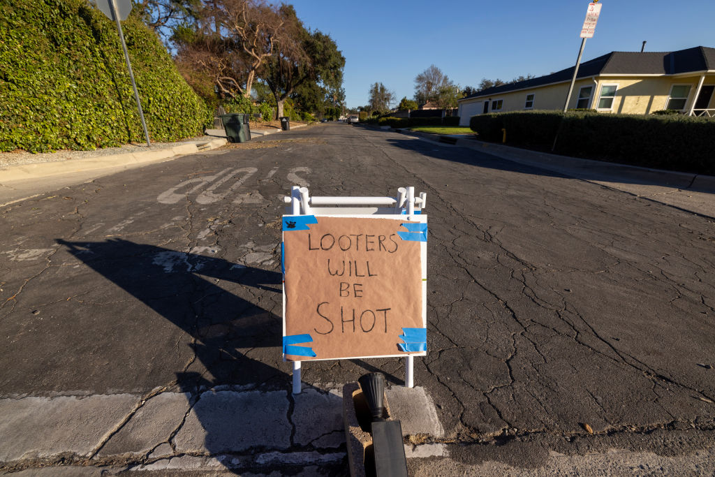 A sign reading 'Looters will be shot' stands in a mandatory evacuation zone at the Eaton Fire on January 12, 2025 in Altadena, Calif.