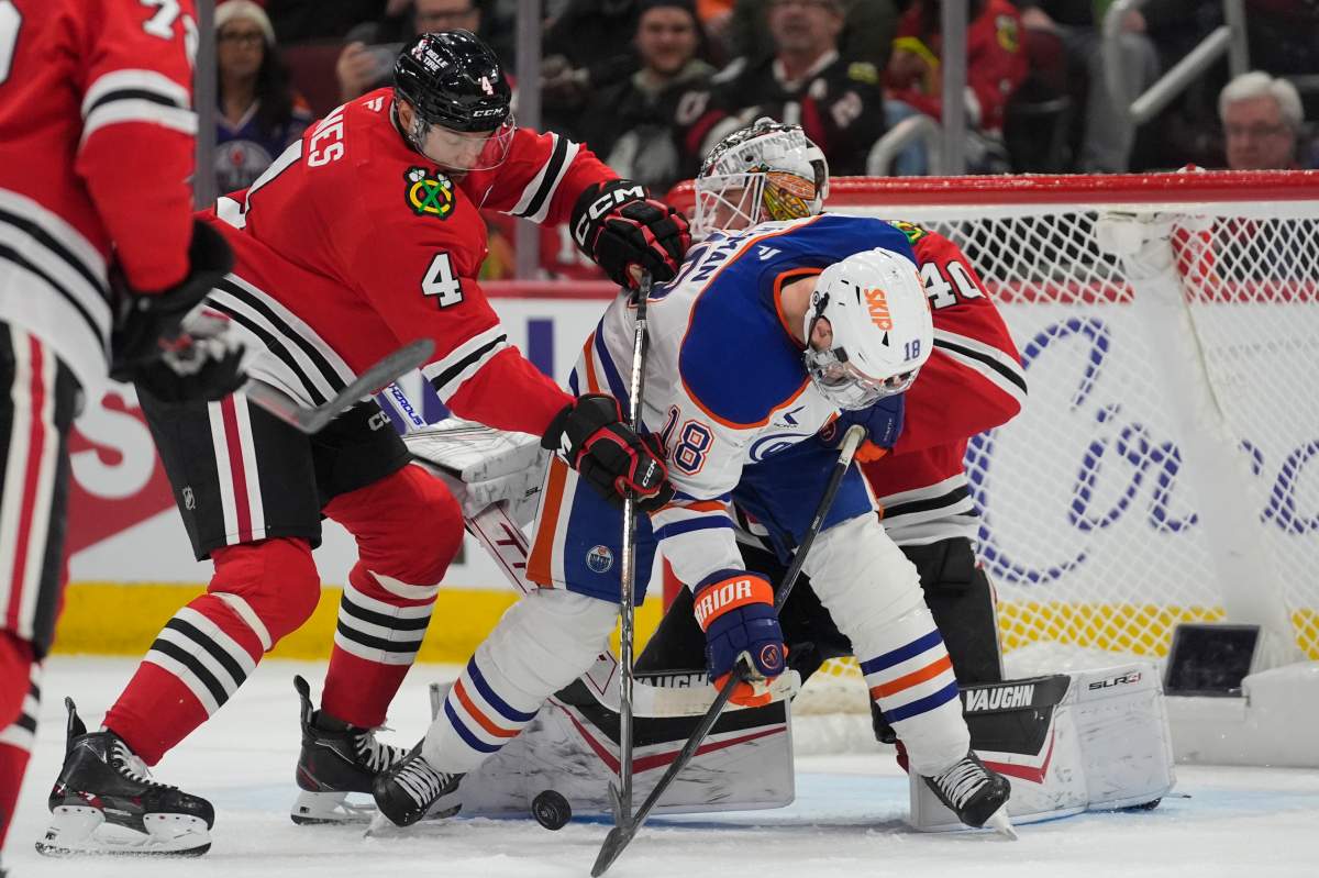 Chicago Blackhawks defenseman Seth Jones (4), left, and Edmonton Oilers forward Zach Hyman (18) scramble for the puck before Hyman scores a goal during the third period of an NHL hockey game Saturday, Jan. 11, 2025, in Chicago.