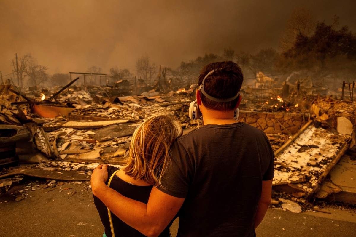 Megan Mantia, left, and her boyfriend Thomas, only first game given, return to Mantia’s fire-damaged home after the Eaton Fire swept through, Wednesday, Jan. 8, 2025 in Altadena, Calif. (AP Photo/Ethan Swope)