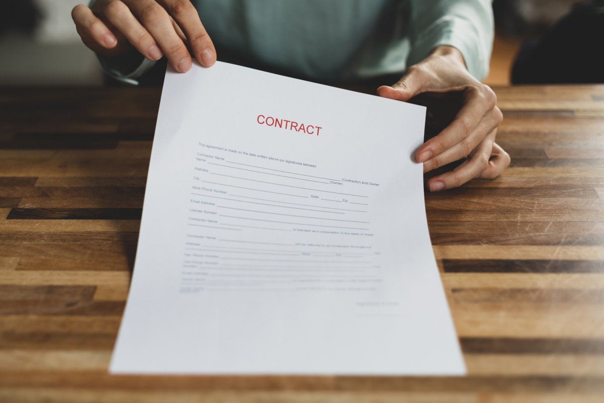 A person placing an employment contract onto a wooden table. Basak Gurbuz Derman / Getty Images