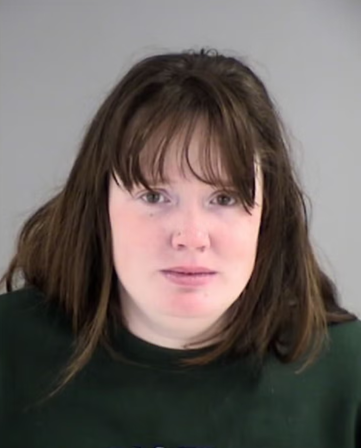 Erin Strotman is pictured in a mugshot, looking into the camera. She has dark hair with bangs and is wearing a green crewneck sweatshirt.