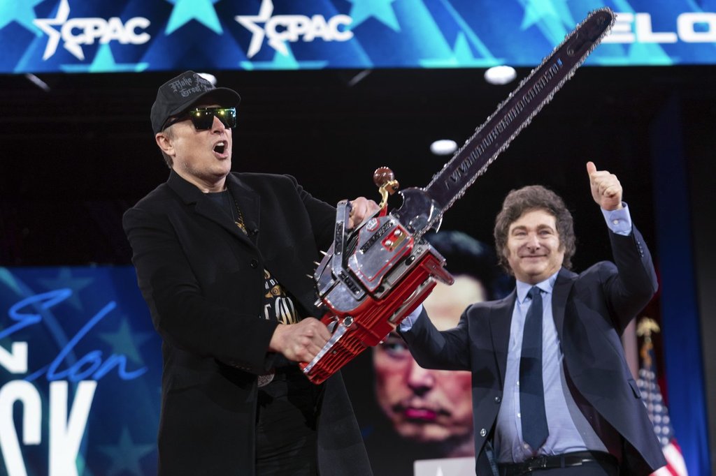 Elon Musk holds up a chainsaw he received from Argentina's President Javier Milei, right, as they arrive to speak at the Conservative Political Action Conference, CPAC, at the Gaylord National Resort & Convention Center, Thursday, Feb. 20, 2025, in Oxon Hill, Md.