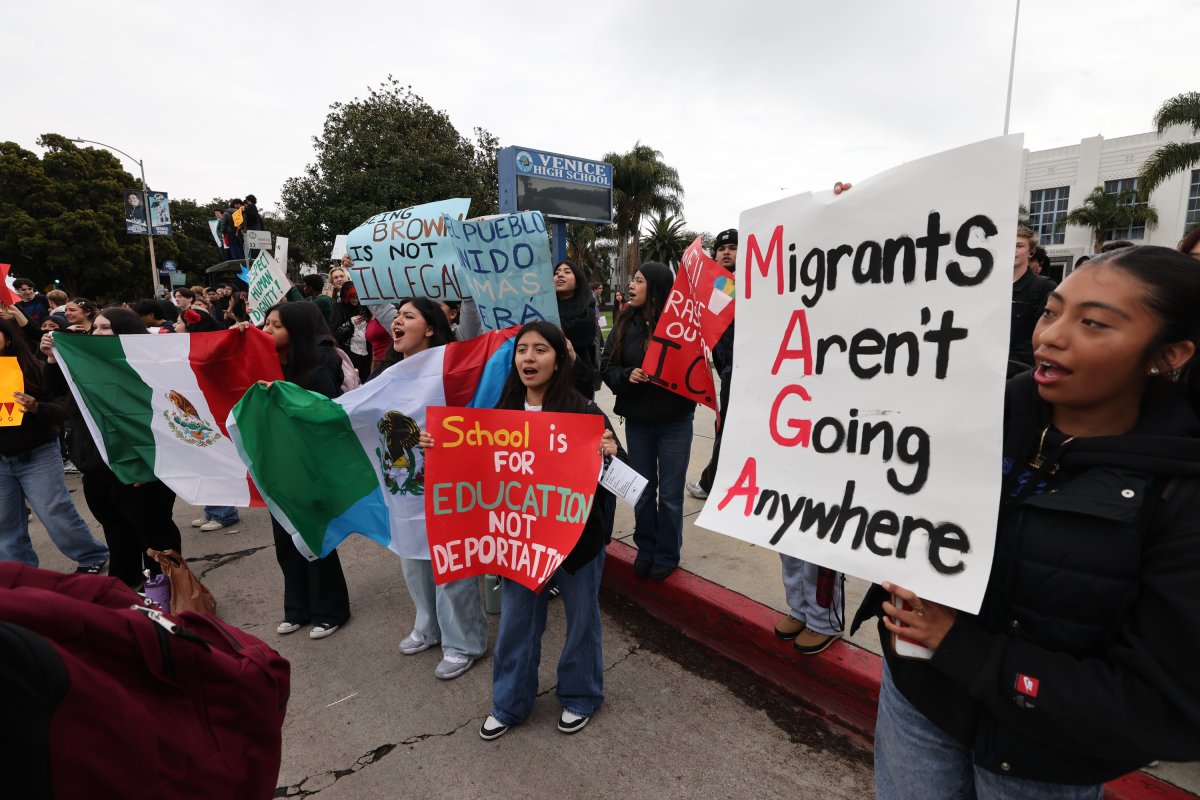 A girl holds MAGA sign reading "Migrants Aren't Going Anywhere" as students from Venice High School protest President Trump administration's immigration policies outside the school.