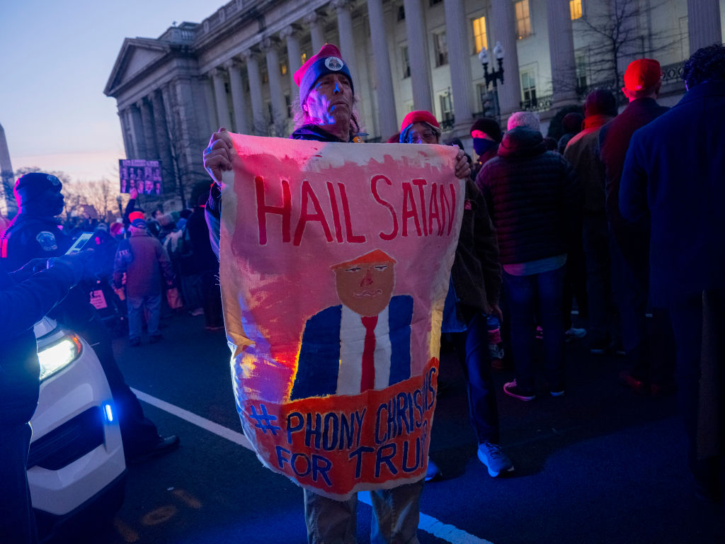 A protester holds a banner that reads "Hail Satan" with a caricature during a rally in front of the U.S. Treasury Department in Washington, D.C., on Feb. 4, 2025.