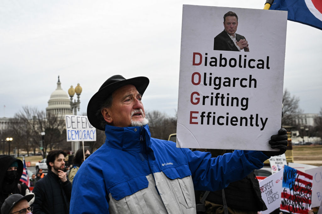 A person holds up a sign as they protest against President Donald Trump and Elon Musk's "Department of Government Efficiency" (DOGE) outside of the US Department of Labor near the US Capitol in Washington, D.C., Feb. 5, 2025.