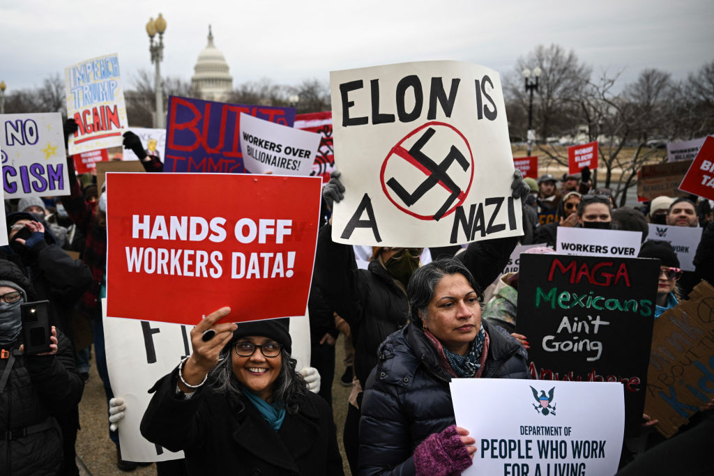 A person holds up a sign as they protest against President Donald Trump and Elon Musk's "Department of Government Efficiency" (DOGE) outside of the US Department of Labor near the US Capitol in Washington, D.C., Feb. 5, 2025.