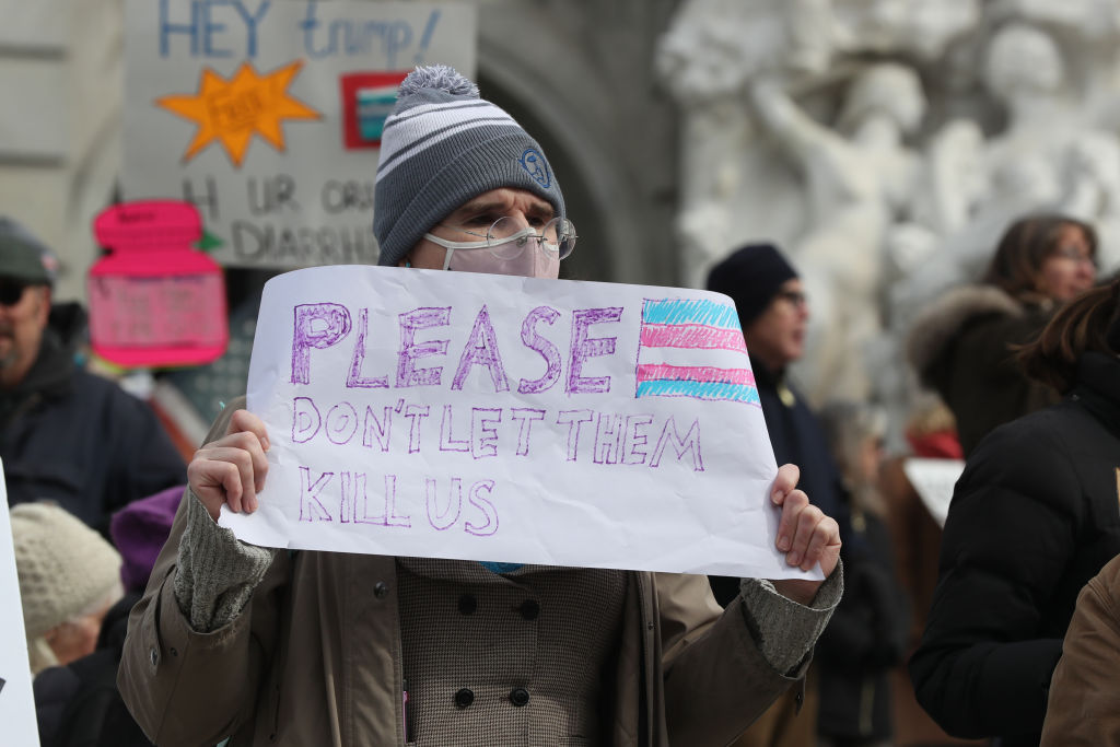 A protester holds a placard outside of the Pennsylvania Capitol during a 50501 protest. The 50501 Movement planned to hold 50 protests in 50 states on one day to protest Trump administration policies and Project 2025.