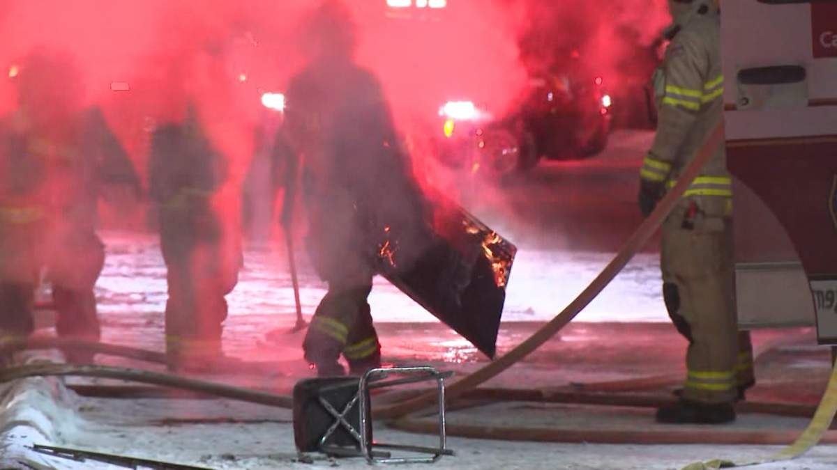 A Calgary firefighter removes a price of burning material from a strip mall on Rundlehorn Drive, near 50th street N.E. early Monday morning.