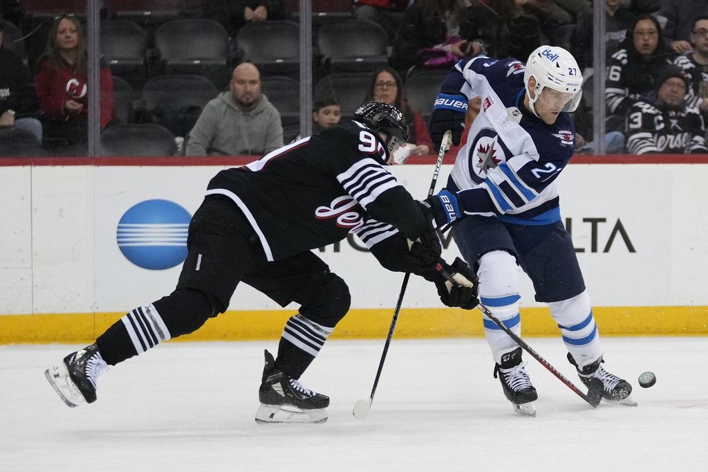 New Jersey Devils' Tomas Tatar, left, fights for control of the puck with Winnipeg Jets' Nikolaj Ehlers (27) during the first period of an NHL hockey game Friday, March 7, 2025, in Newark, N.J. (AP Photo/Frank Franklin II).