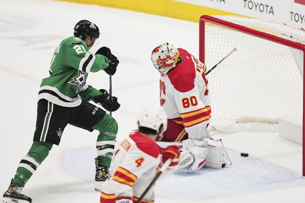 Dallas Stars left wing Jason Robertson (21) scores against Calgary Flames goaltender Dan Vladar (80) as Flames' Rasmus Andersson (4) looks on in overtime of an NHL hockey game in Dallas, Thursday, March 6, 2025.