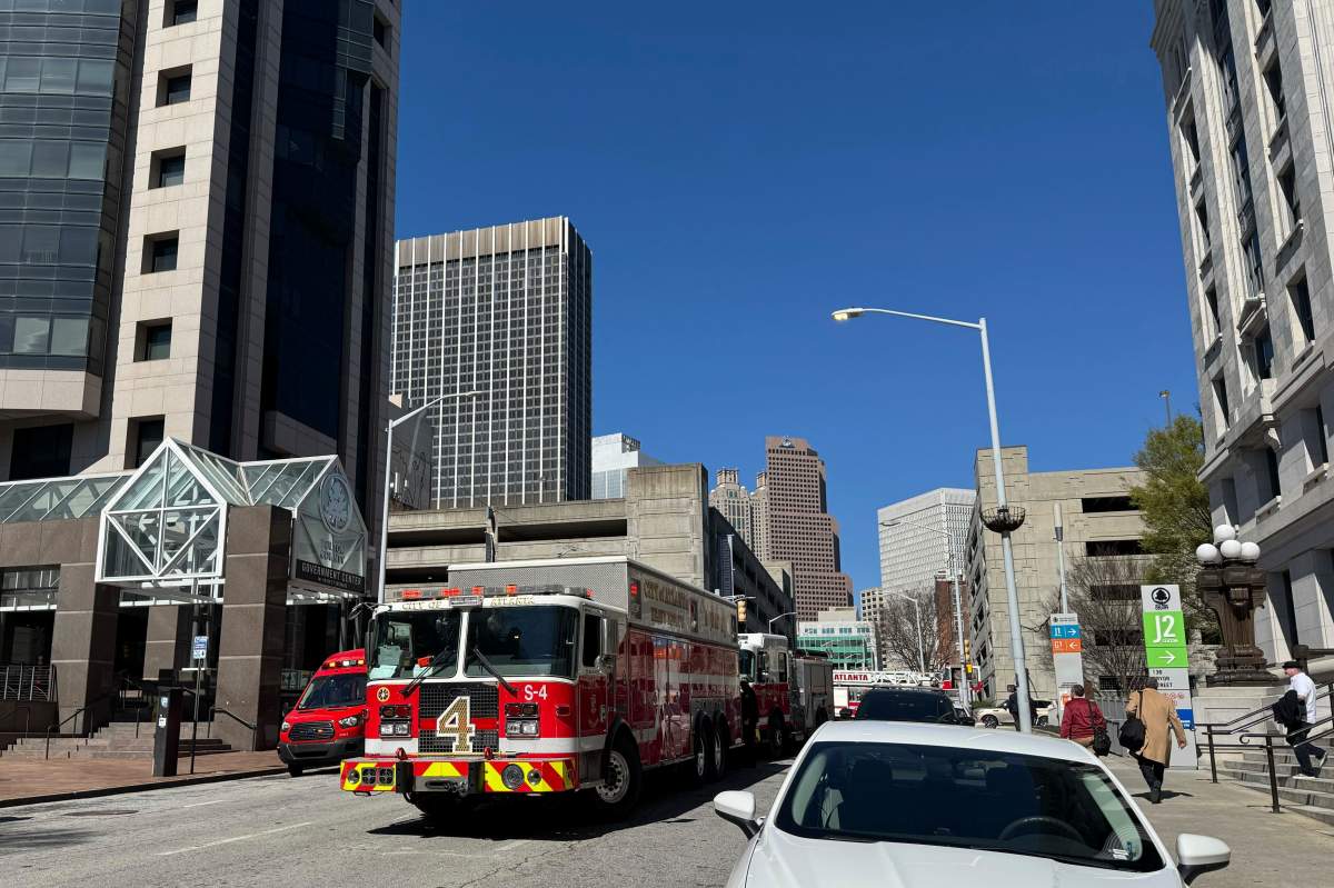Fire engines are parked in front of Fulton County Courthouse, right, as part of the Atlanta courthouse was evacuated Friday, March 21, 2025, after a package with suspicious white powder was delivered to the office of Fulton County District Attorney Fani Willis. (AP Photo/Charlotte Kramon).