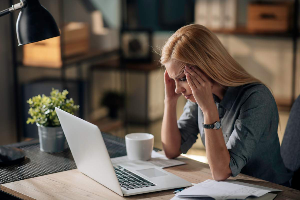 A businesswoman reads an upsetting email on her laptop.
