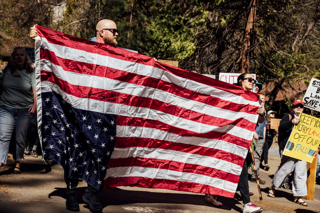Protesters hold an inverted U.S. flag, a symbol of distress, during a national day of action against Trump administration's mass firing of National Park Service employees at Yosemite National Park, Calif., Saturday, March 1, 2025.