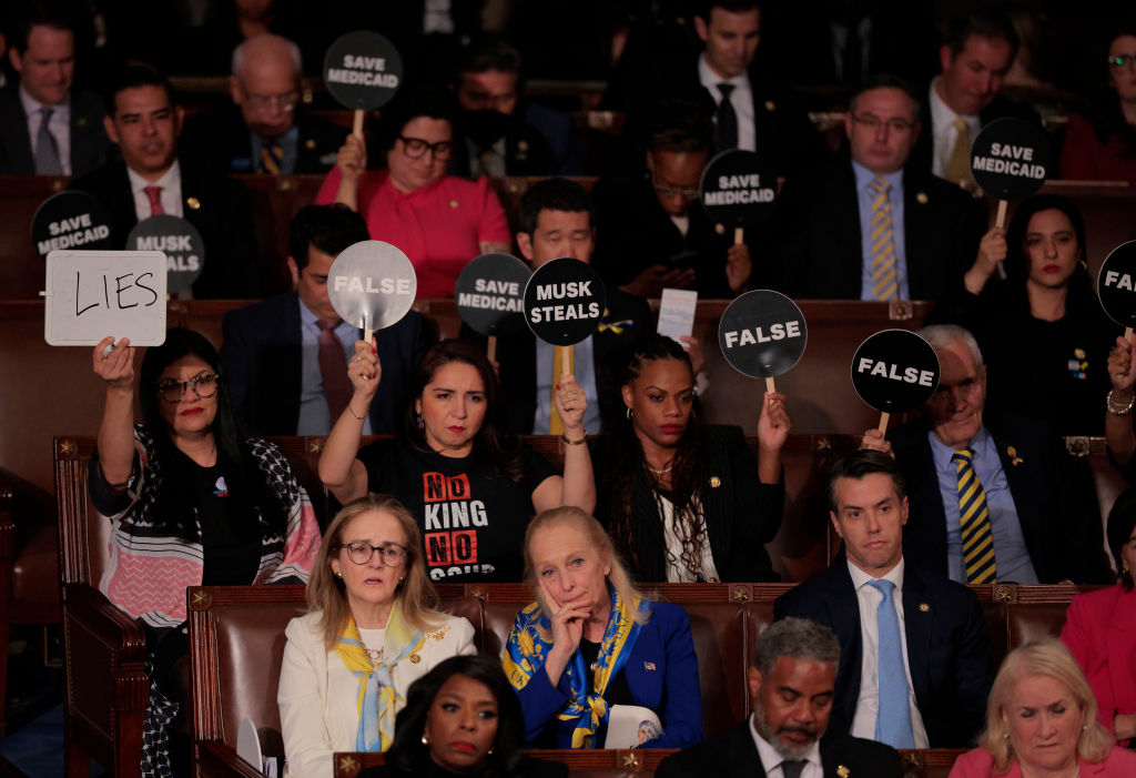 Democratic members of Congress hold up signs in protest as U.S. President Donald Trump addresses a joint session of Congress at the U.S. Capitol on March 04,(Photo by Chip Somodevilla/Getty Images)