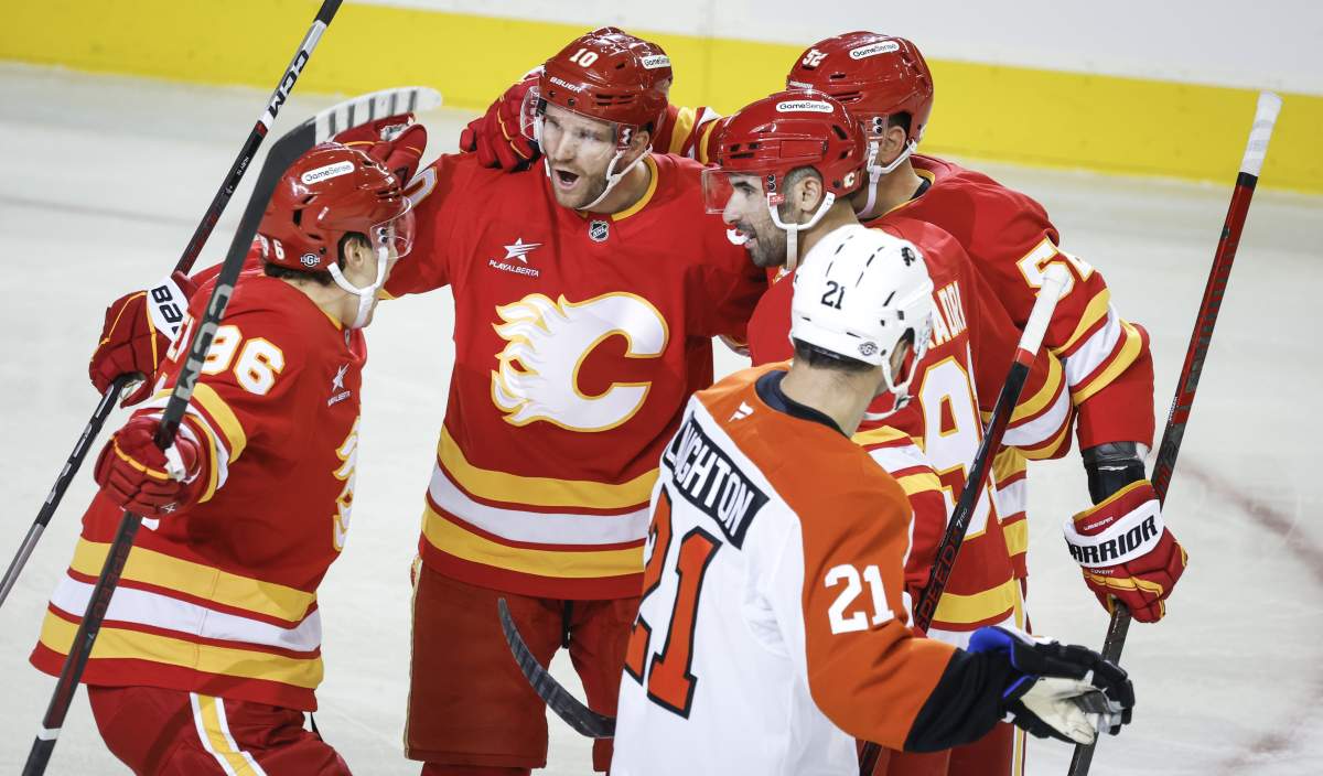 Philadelphia Flyers' Scott Laughton, right, skates past as Calgary Flames' Jonathan Huberdeau, second left, celebrates his goal with teammates during first period NHL hockey action in Calgary on Saturday, Oct. 12, 2024.