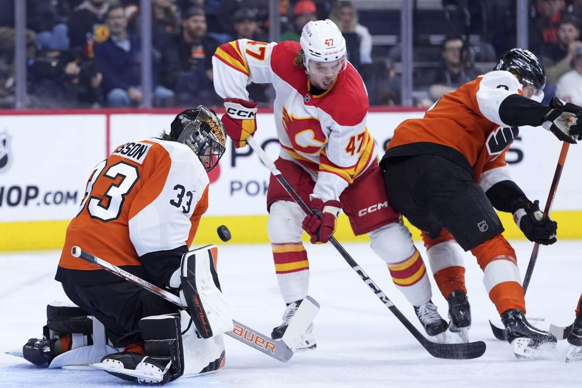 Calgary Flames' Connor Zary, centre, scores a goal against Philadelphia Flyers' Samuel Ersson, left, and Cam York during the first period of an NHL hockey game Tuesday, March 4, 2025, in Philadelphia.