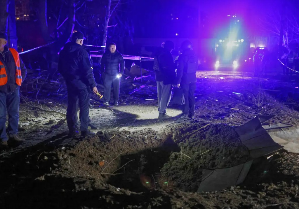 Police officers look at a crater made by a drone near apartment houses following Russia's night attack in Kharkiv, Ukraine, late Saturday, March 29.