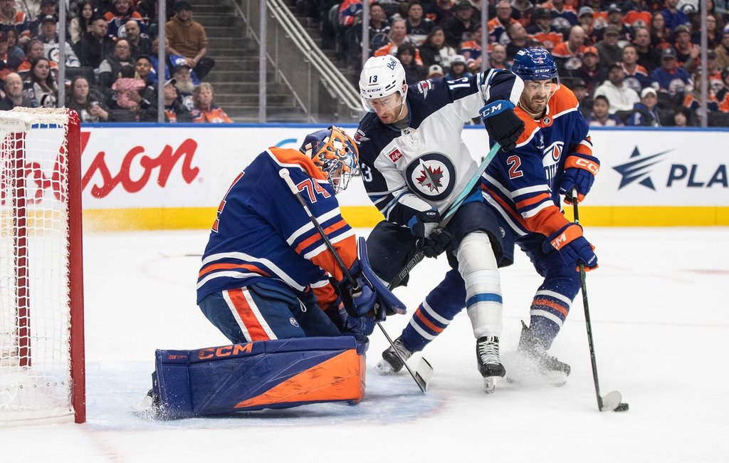 Winnipeg Jets' Gabriel Vilardi (13) and Edmonton Oilers' Evan Bouchard (2) battle in front as goalie Stuart Skinner (74) makes the save during first period NHL action in Edmonton on Thursday, March 20, 2025. THE CANADIAN PRESS/Jason Franson.