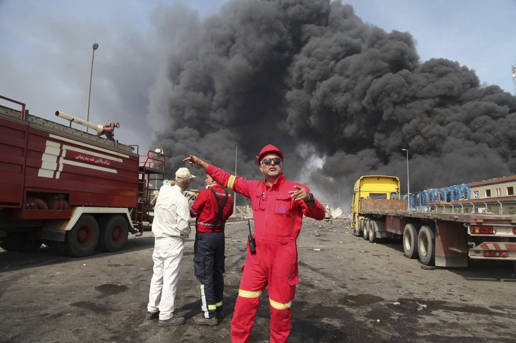 In this photo provided by Islamic Republic News Agency (IRNA) firefighters work as black smoke rises in the sky after a massive explosion rocked a port near the southern city of Bandar Abbas.