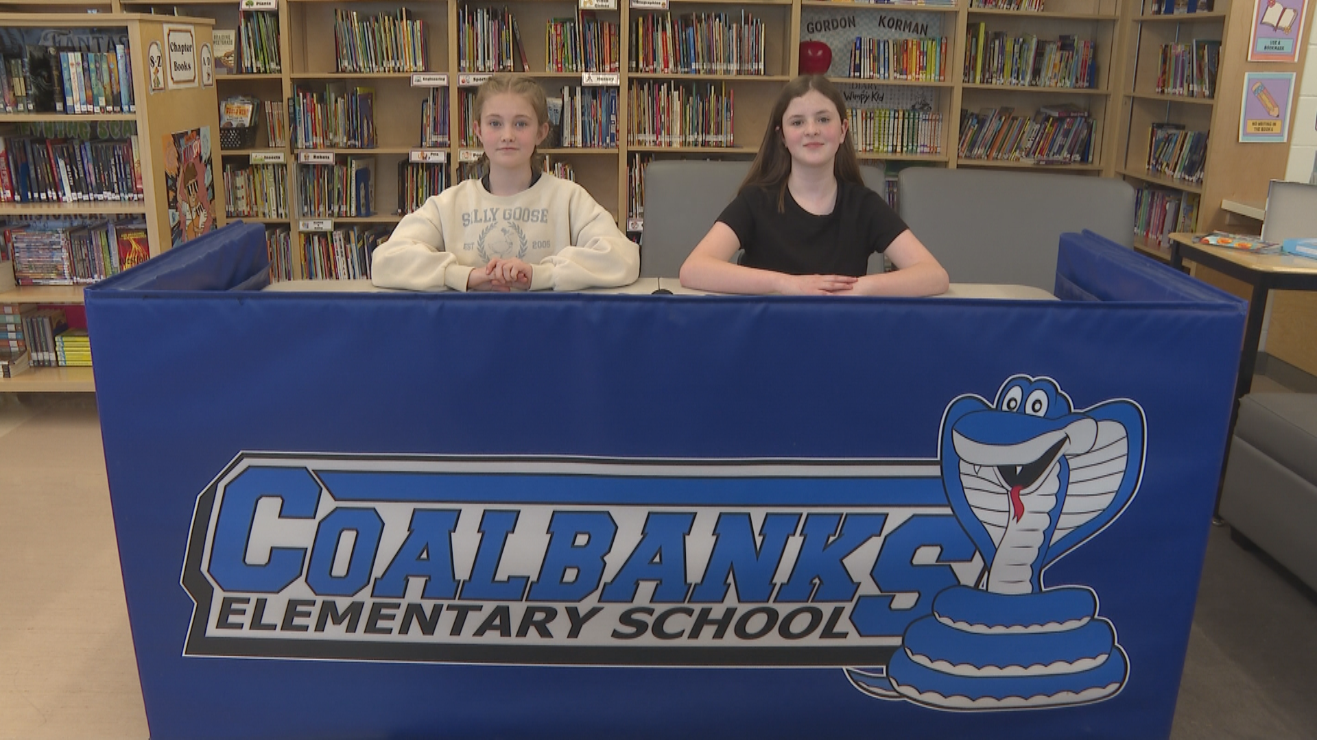 Two students at a makeshift news desk.