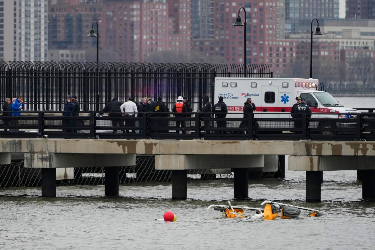 First responders stand on a pier at the scene where a helicopter crashed into the Hudson River, Thursday, April 10, 2025, in Jersey City, N.J. (AP Photo/Seth Wenig)