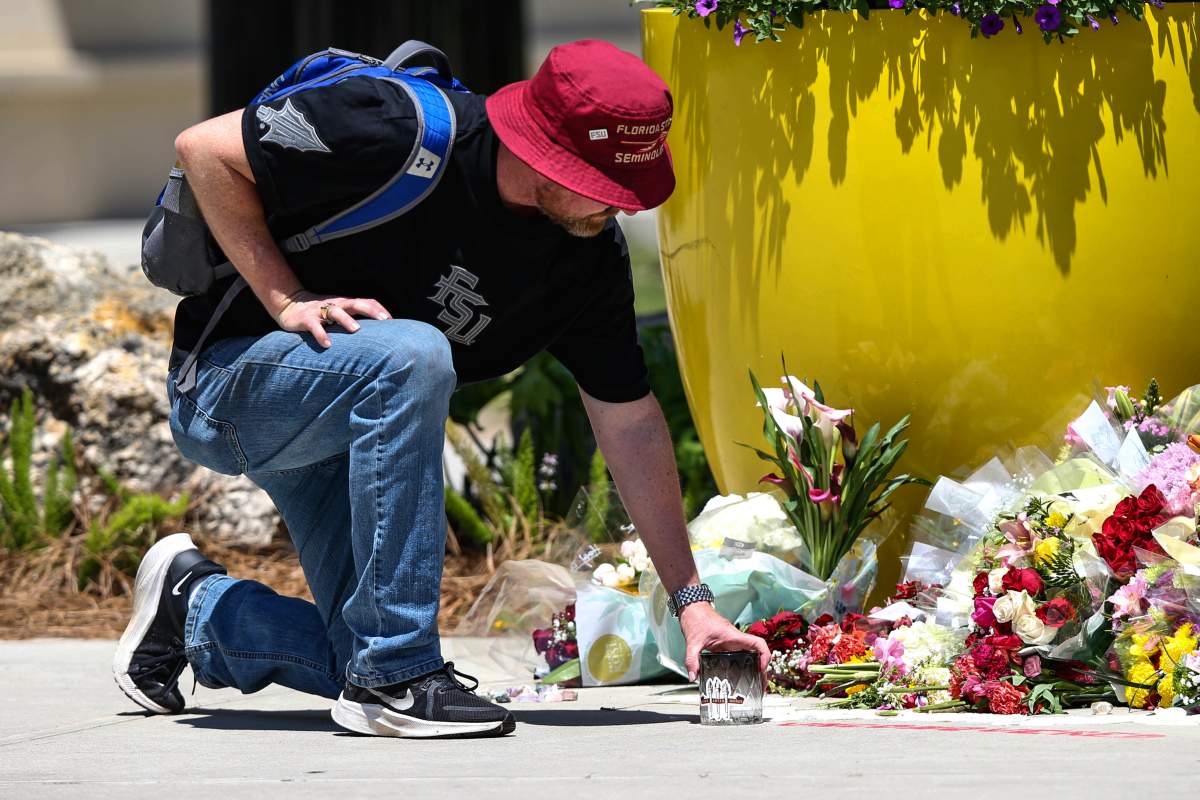 A student places a candle near the Florida State Student Union building, Tallahassee, Fla., Friday, April 18, 2025.