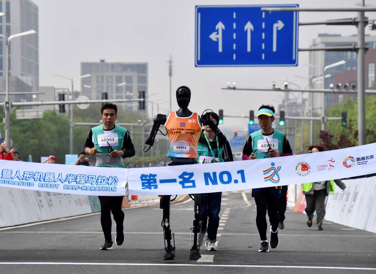 Robotic participant "Tiangong Ultra" C competes as engineers run alongside during the Beijing E-Town half-marathon and humanoid robots half-marathon in the Beijing Economic-Technological Development Area in southeast Beijing, China, April 19, 2025.