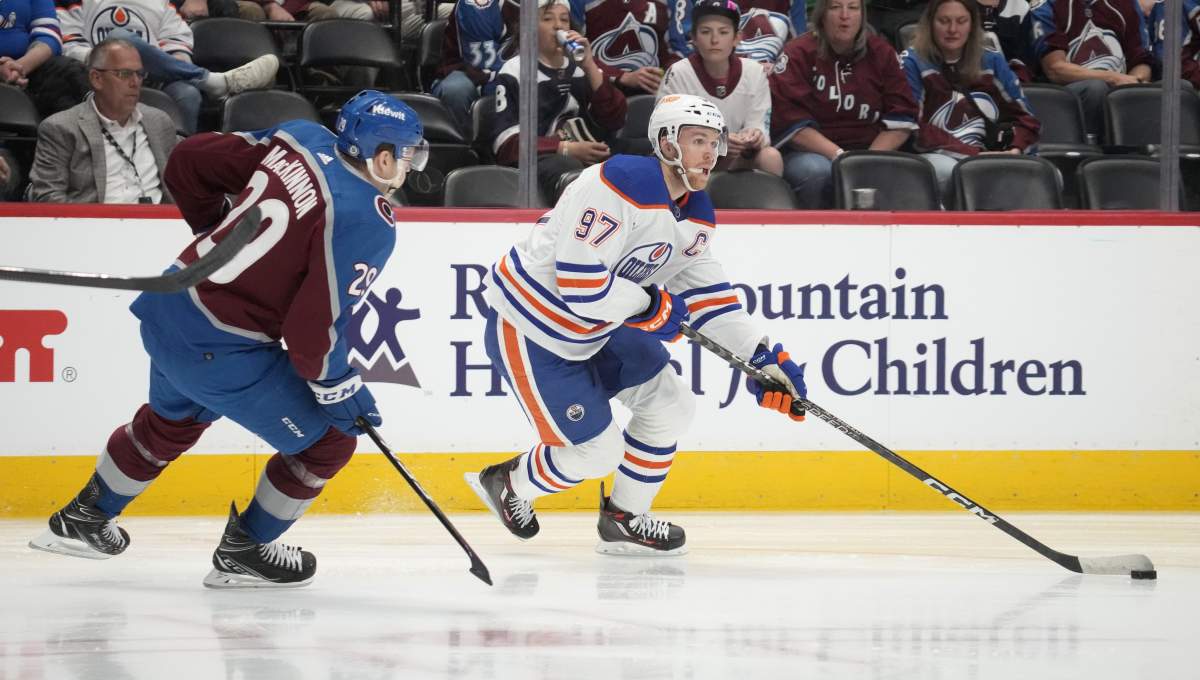 Edmonton Oilers centre Connor McDavid, right, collects the puck as Colorado Avalanche centre Nathan MacKinnon defends in the second period of an NHL hockey game Tuesday, April 11, 2023, in Denver.
