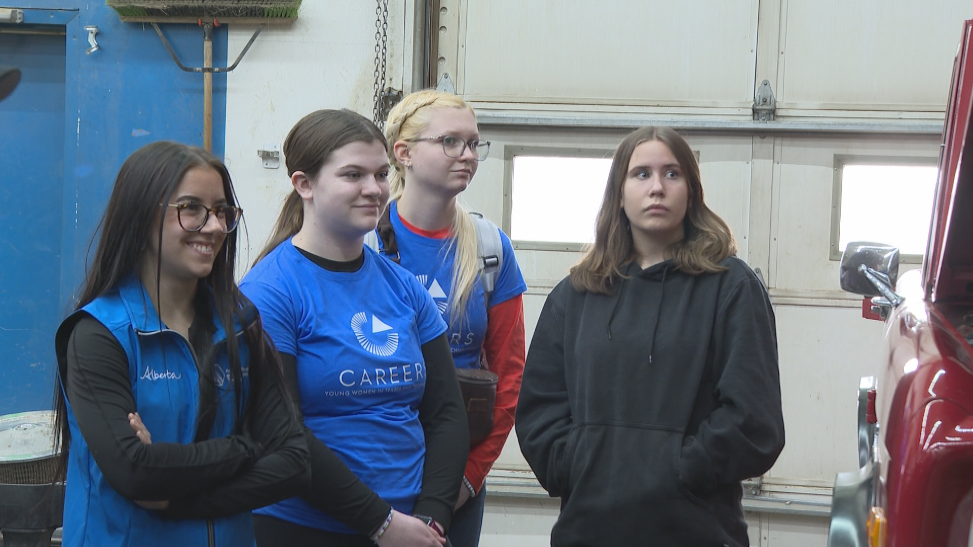 A group of students in an auto mechanic shop.