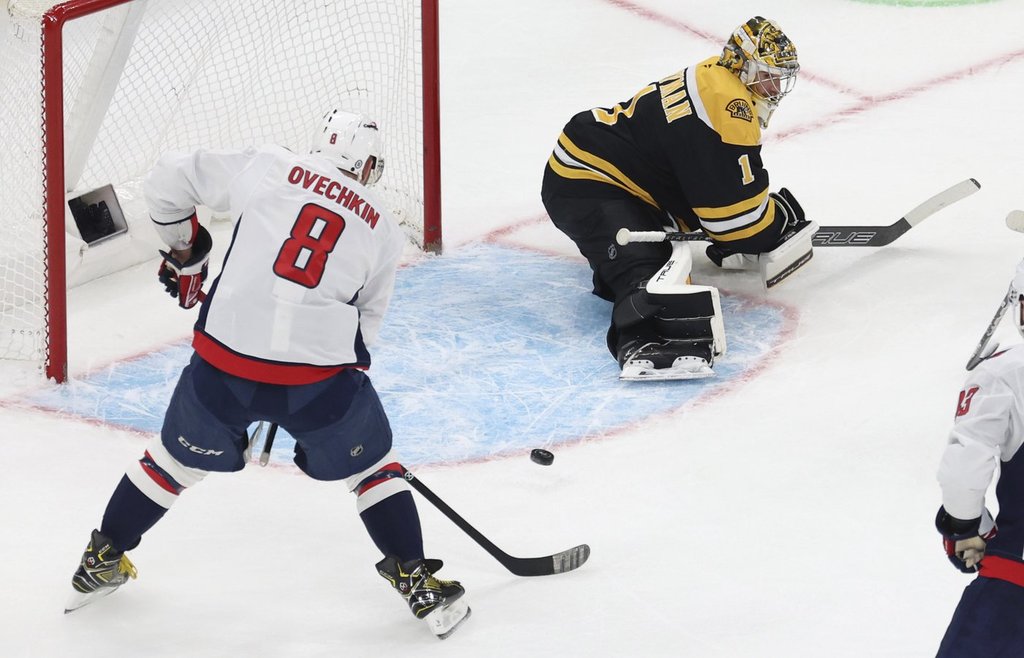 Washington Capitals left wing Alex Ovechkin (8) hits the puck past Boston Bruins goaltender Jeremy Swayman (1) to score during the first period of an NHL hockey game, Tuesday, April 1, 2025, in Boston.