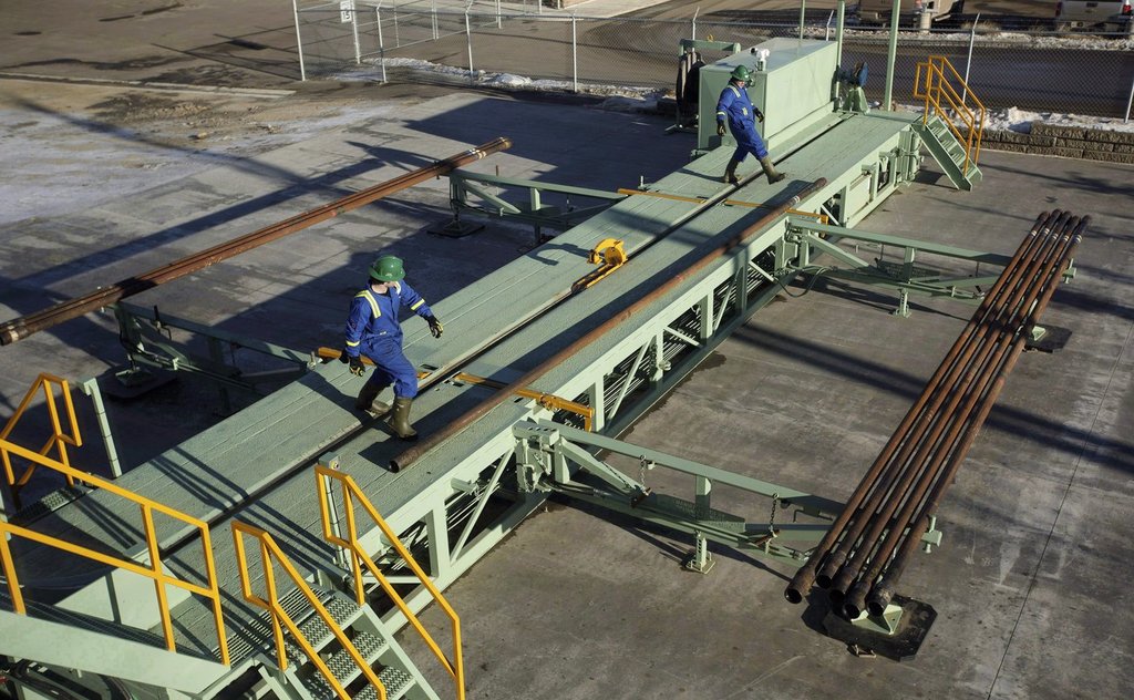 Trainees roll pipe off the catwalk during a training session to lay down drill pipe on a rig floor at Precision Drilling in Nisku, Alta., in a Jan. 20, 2017, file photo.
